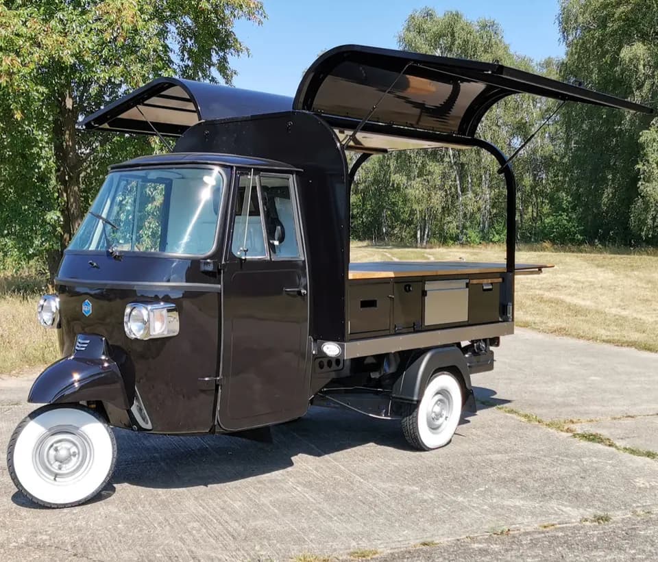 Schwarze Ape mit aufgeklapptem Dach als mobile Kaffeebar