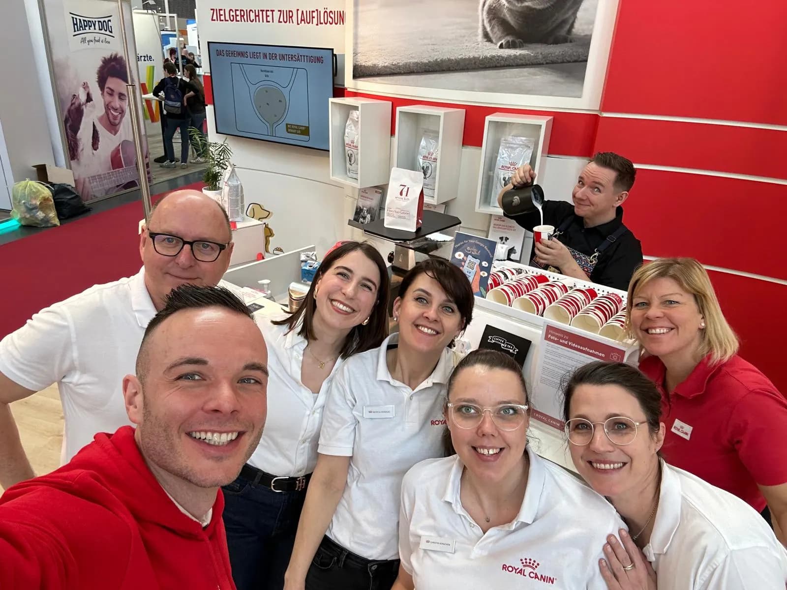 Team an einem Messestand, im Hintergrund gießt ein Barista Kaffee