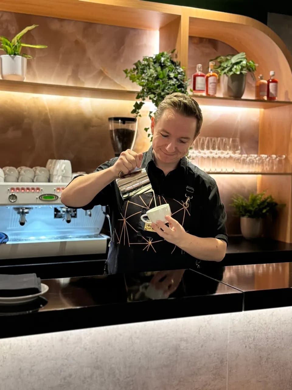 Barista gießt an einer Bar in einer Lounge ein Milchgetränk
